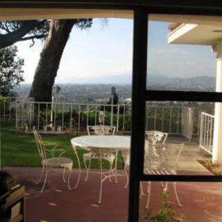 A scenic view from a patio with outdoor furniture overlooking a garden and landscape.