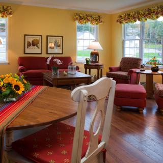 A cozy living room with traditional decor, featuring red sofas, yellow walls, and wooden furniture.