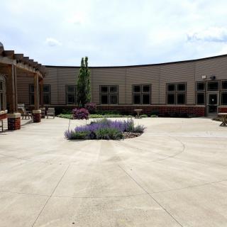 A courtyard featuring a central garden with flowers, surrounded by a building with multiple windows.