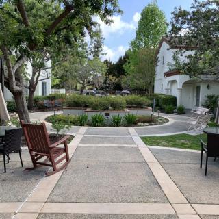 A peaceful garden with chairs and a paved pathway surrounded by greenery.