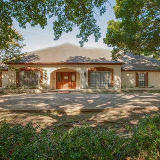 A charming single-story house surrounded by trees and a spacious driveway.