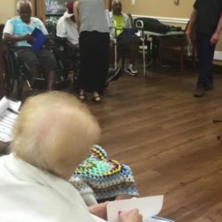 A group of seniors engaging in an indoor activity at a nursing home.