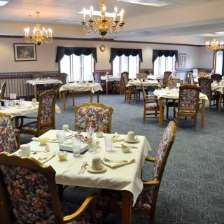 An elegant dining room with neatly set tables and ornate chandeliers.