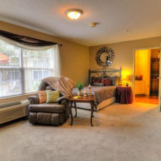 A cozy bedroom interior with a large window, comfortable chair, and well-arranged furniture.