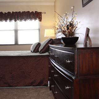 A cozy bedroom with a wooden dresser, bed, and decorative accents.