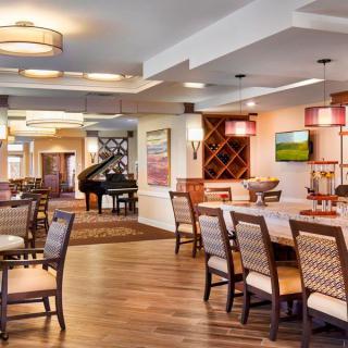 A modern and spacious dining area with elegant furniture and a piano.