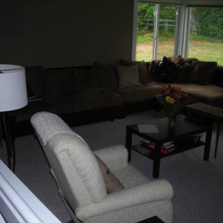 A cozy living room with a sofa, armchair, and coffee table by the window.