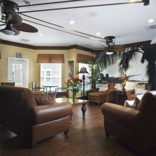 A cozy living room with leather chairs, wood flooring, and abundant natural light.