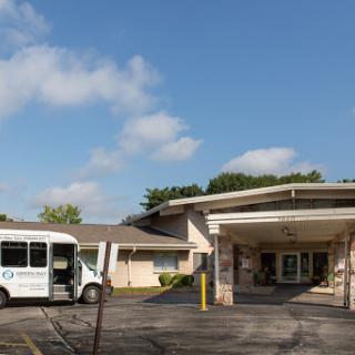 A view of a residential building with a bus parked nearby under a clear blue sky.