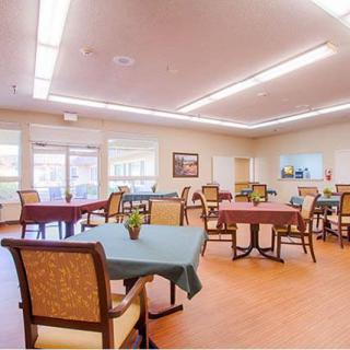 A spacious dining room with neatly arranged tables and chairs, featuring bright lighting and a welcoming atmosphere.