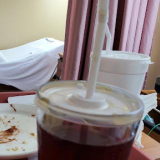 A close-up of a drink near a food tray in a hospital setting.