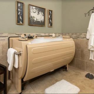 A unique vertical bathtub in a stylishly decorated bathroom with towels and artwork.