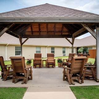 An inviting outdoor gazebo with wooden seating arrangement on a patio.