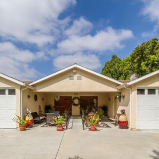 A suburban house with a driveway and two garages under a blue sky.