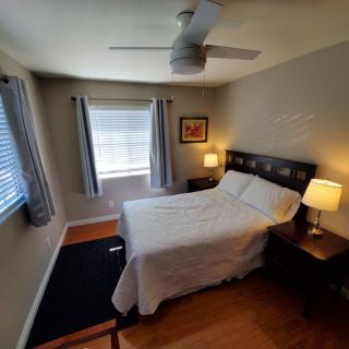 A cozy bedroom with a double bed, ceiling fan, and warm lighting.