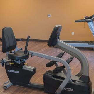A recumbent bike in a gym with wood flooring.