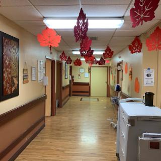 A decorated hospital corridor with autumn-themed leaf decorations hanging from the ceiling.