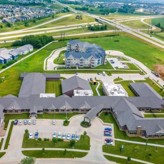 Aerial view of suburban infrastructure with buildings and roads surrounded by greenery.