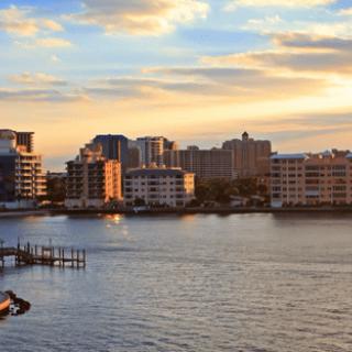 A stunning view of a city skyline over a calm waterfront during sunset.
