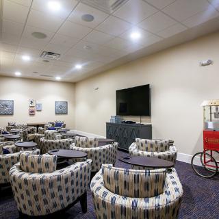 A cozy lounge area with numerous chairs, a large television, and a popcorn machine.