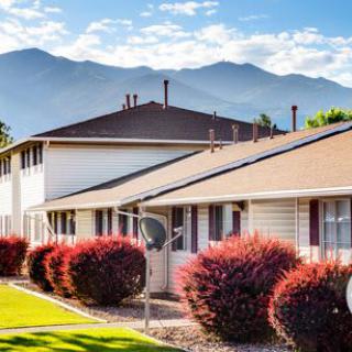 A row of houses with a backdrop of mountains under a clear sky.