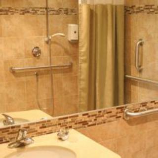 A cozy bathroom featuring a shower with a curtain, a sink, and tiled walls.