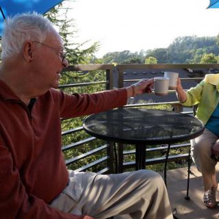 An elderly couple enjoying coffee together on a scenic patio.