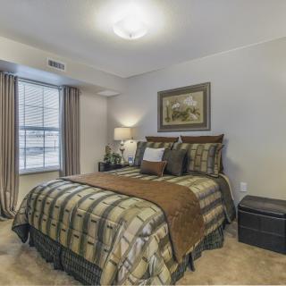 A cozy bedroom with a neatly made bed, warm lighting, and tasteful decor.