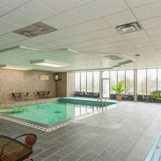 An indoor swimming pool with seating areas and large windows.