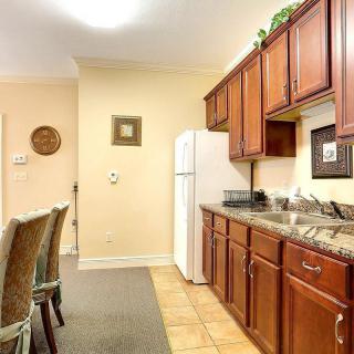 A cozy kitchen with wooden cabinets, a countertop, and a row of chairs along the side.