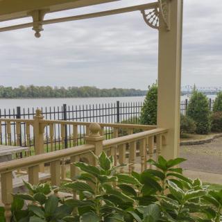 A tranquil porch overlooking a lake with a cloudy sky.