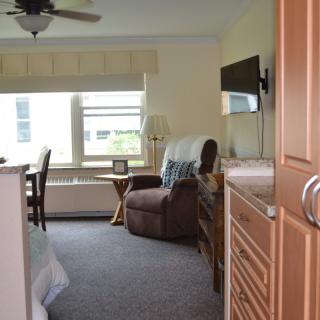 A cozy bedroom with a recliner chair, television, and large windows.