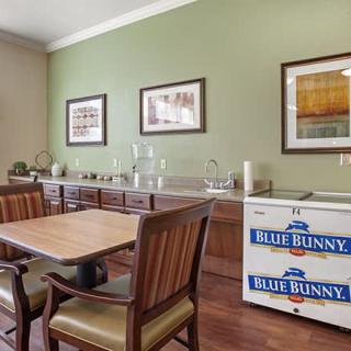 A dining room with wooden furniture, artwork on the walls, and a small freezer in the corner.