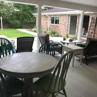 A cozy patio setup with a round table and various chairs in a covered outdoor area.