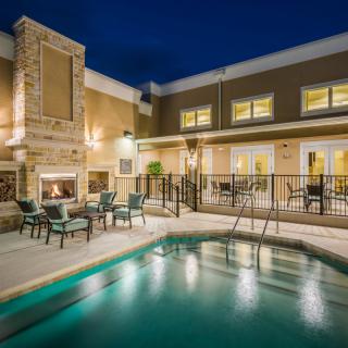 A cozy outdoor pool area at night with a fireplace and seating.