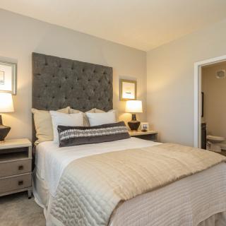 A cozy and well-decorated bedroom featuring a plush bed with a tufted headboard, complemented by two lamps on nightstands.