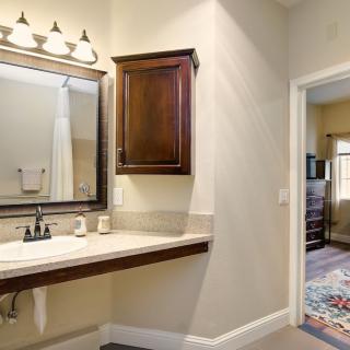 A well-lit bathroom features a vanity with a sink, mirror, and wooden cabinet.