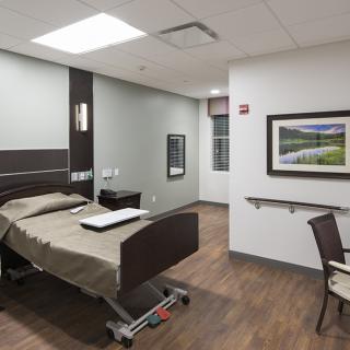 A modern hospital room featuring a bed and clean, minimalist design.