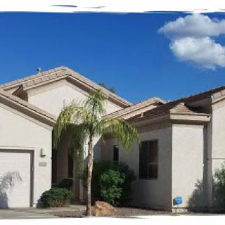 A beautiful residential house with a palm tree under a clear blue sky.