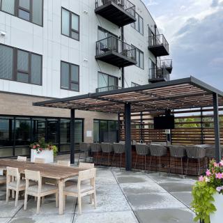 A modern outdoor seating area with a bar and tables next to an apartment building.
