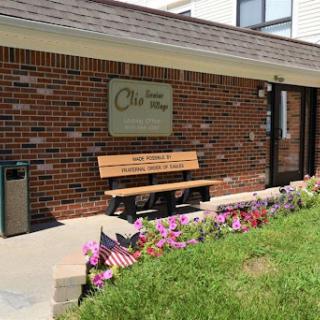 A welcoming entrance with a bench and flowers in front of a brick building.