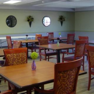 An empty dining area with wooden tables and chairs, decorated with small vases and wall ornaments.