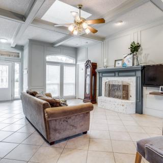 A spacious living room with a cozy sofa and fireplace, featuring large windows and elegant tile flooring.