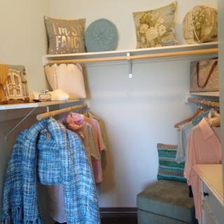 A neatly organized closet featuring hanging clothes and decorative pillows on the shelves.