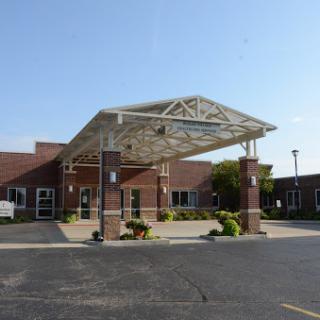 A modern medical facility entrance with a structured canopy and well-maintained landscaping.
