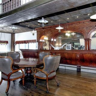 A vintage-style room featuring an elegant wooden bar and antique dining furniture.