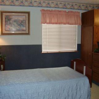 A bedroom with a single bed, window blinds, and a wardrobe.