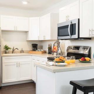A modern kitchen featuring white cabinets and stainless steel appliances, complete with a cozy breakfast setup.