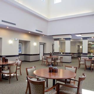 A spacious dining room with tables and chairs arranged neatly, featuring modern lighting and decor.