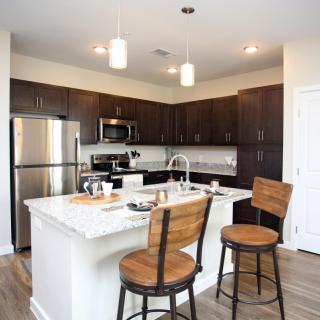 A modern kitchen featuring a central island with bar stools and stainless steel appliances.